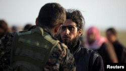 A fighter from Syrian Democratic Forces (SDF) checks a man near the village of Baghouz on February 22. 