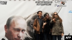 Люди делают селфи у плаката с изображением президента России Владимира Путина в Санкт-Петербурге. Иллюстративное фото.
