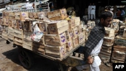 A Pakistani laborer pulls a cart loaded with mango crates at a fruit market in Islamabad.
