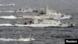 A Chinese marine surveillance ship Haijian (center) cruises next to Japanese coast guard ships in the East China Sea, near islands known as the Senkakus in Japan and the Diaoyus in China.