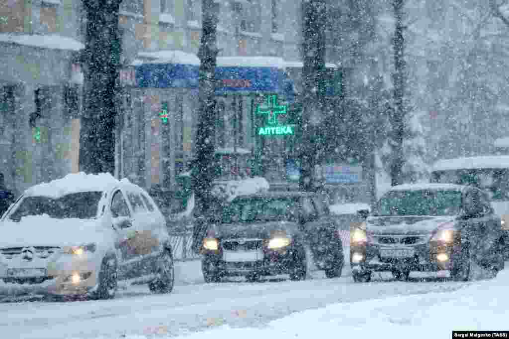 Автомобили во время снегопада на одной из улиц Симферополя