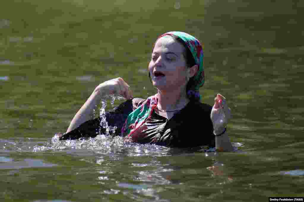 A pilgrim crosses herself as she takes a dip in the Velikaya River.