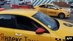 An Uber car (back) and a Yandex.Taxi car on the streets of Moscow in July.
