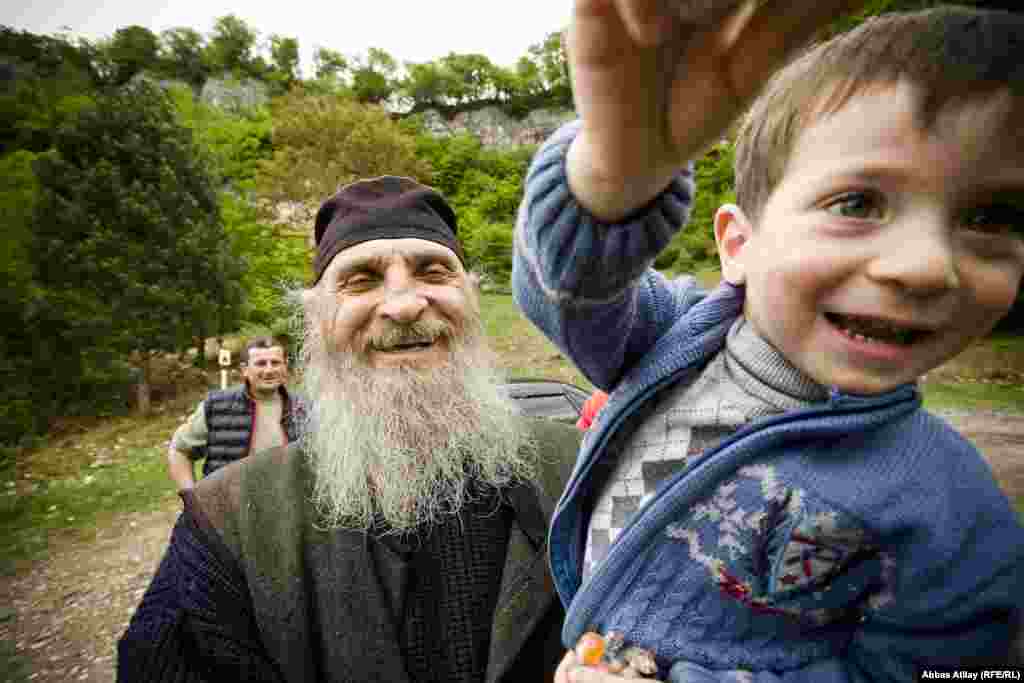 Rahib Maksim Kavtaradze balaca ziyarətçisini ucağına alıb əzizləyir.