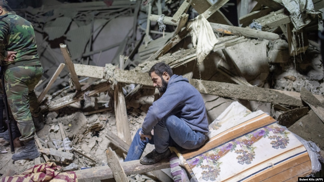 A man sits amid rubble following shelling in the town of Ganca, near the front lines in Nagorno-Karabakh. 