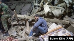 A man sits amid rubble following shelling in the town of Ganca, near the front lines in Nagorno-Karabakh. 