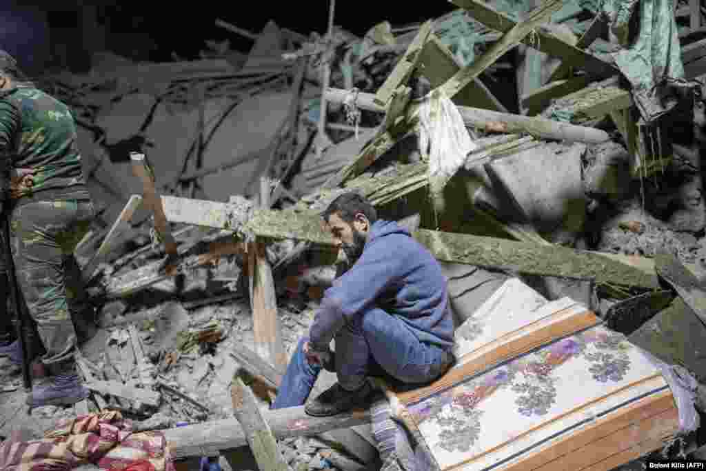 A resident sits amid the rubble as rescuers search for his relatives after a rocket hit a residential area in Ganca, Azerbaijan&rsquo;s second-largest city, on October 17.