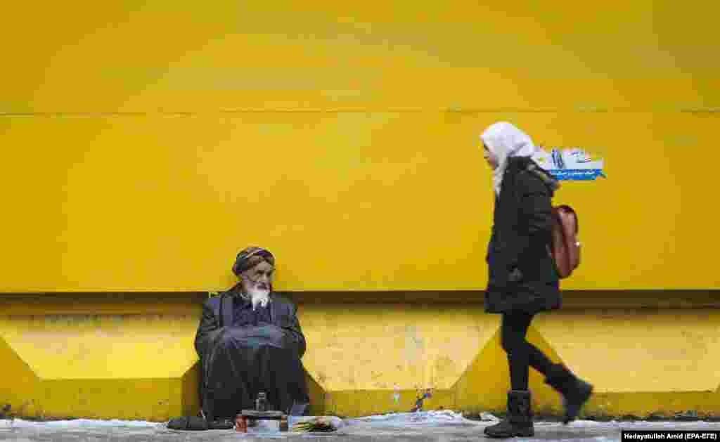An Afghan shoe-shiner sits on a Kabul street as he waits for customers. (epa-EFE/Hedayatullah Amid)&nbsp;&nbsp;