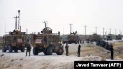 NATO soldiers keep watch near the wreckage of their vehicle at the site of a Taliban suicide attack in Kandahar on September 15.