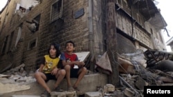 Syria - Children sit along a damaged street filled with debris in the besieged area of Homs September 19, 2013