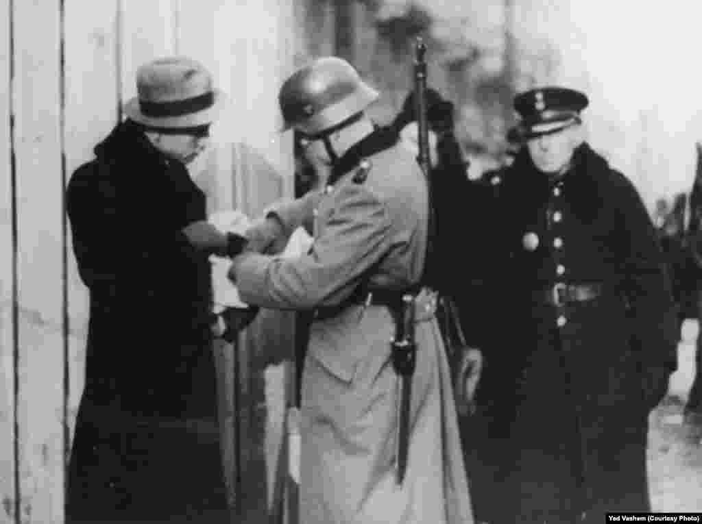 A German soldier inspects a Jew&#39;s documents. 