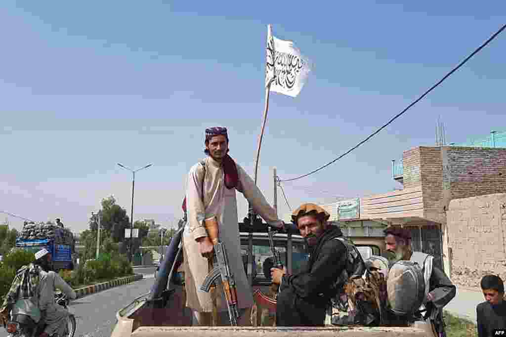 Taliban fighters drive an Afghan National Army vehicle through the streets of the eastern Laghman Province on August 15. Tens of thousands of Afghans have fled their homes, many fearing a return to the Taliban&#39;s oppressive rule.