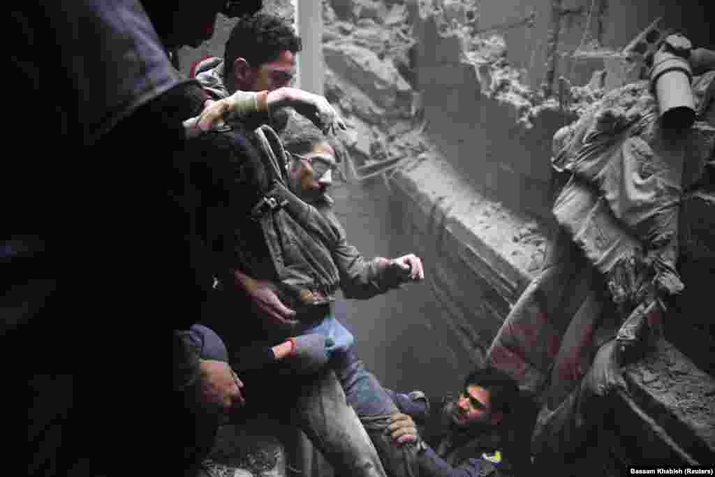 Rescue workers help a man from a shelter in the besieged town of Douma in eastern Ghouta Syria, on February 22. (Reuters/Eric Gaillard)