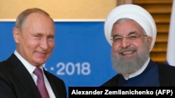 Ресей президенті Владимир Путин (сол жақта) мен Иран президенті Хассан Роухани ШЫҰ саммитінде. Циндао, Қытай, 9 маусым 2018 жыл.