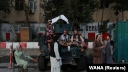 Afganistan: një grup talibanësh qëndrojnë pranë një automjeti ushtarak në Kabul, më 1 shtator, 2021. 