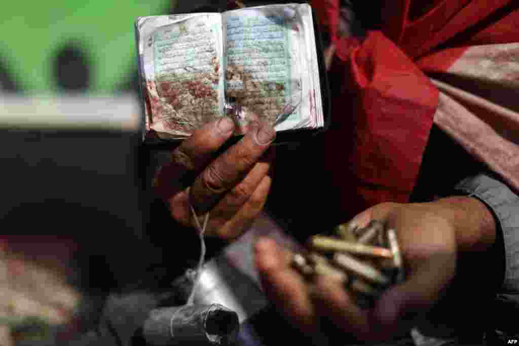 An Egyptian supporter of deposed President Muhammad Morsi holds a copy of the Koran stained with blood and empty casing as he attends a rally in support of the former Islamist leader outside Cairo&#39;s Rabaa al-Adawiya Mosque. (AFP/Mahmud Hams)