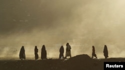 Women clad in burqas walk along a street as the sun sets in Kabul. (file photo)