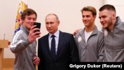 President Vladimir Putin (second left) poses for a selfie during a meeting on January 31 with Russian athletes and team members who will take part in the upcoming Winter Olympic Games as neutral athletes.