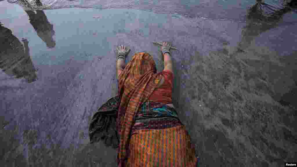 A Hindu devotee prostrates herself in the sands near the Arabian Sea as she worships the Sun god during the Hindu religious festival Chhat Puja in Mumbai, India. During the festival, Hindu devotees worship the Sun god and fast all day for the betterment of their family and society. (Reuters/Vivek Prakash)
