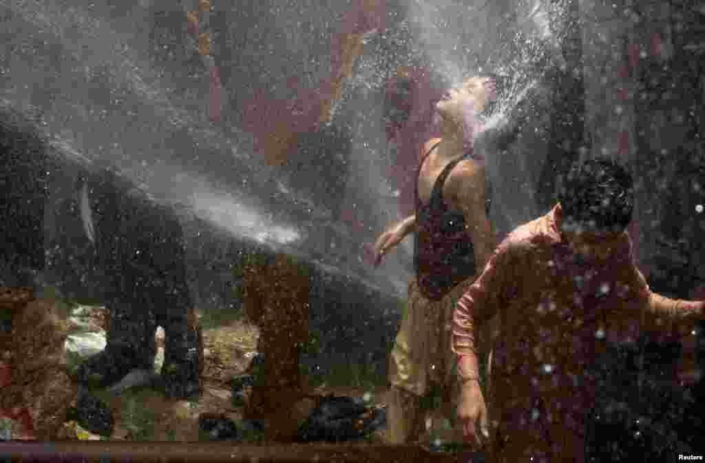 A boy cools off with the help of water lines punctured in protest at power outages in Karachi, Pakistan. (Reuters/Akhtar Soomro)