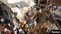 Residents and rescue workers gather at the site of a mosque, after its roof collapsed, in Lahore on September 9, 2014.