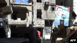 A man walks under a portrait of Syrian President Bashar al-Assad in a street inside the Yarmouk Palestinian refugee camp in the Syrian capital on April 6.