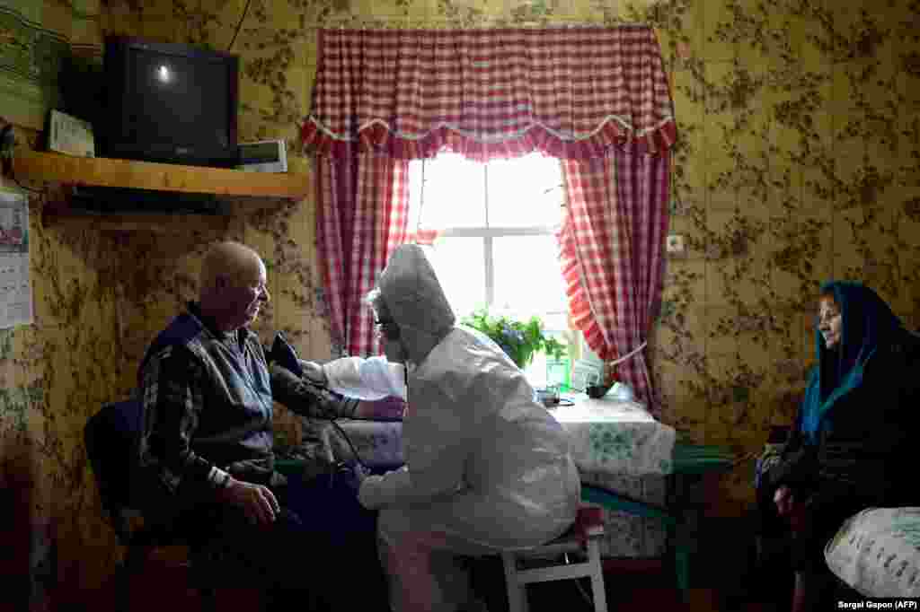 A paramedic wearing a protective suit inspects a patient in the Belarusian village of Novaya Obol, some 70 kilometers outside Vitebsk. (AFP/Sergei Gapon)