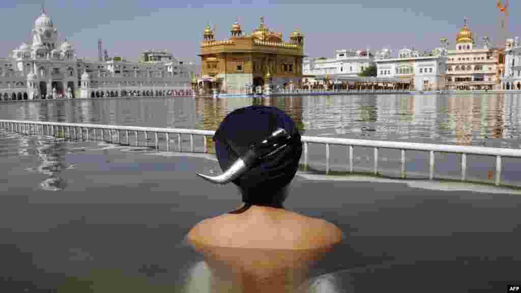 A Sikh devotee takes a holy dip in the sarover (water tank) at the Sikh Shrine Golden Temple in Amritsar, India, on April 12. (AFP/Narinder Nanu)