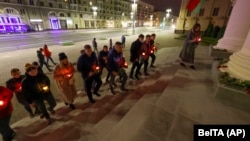 People carry candles to the Belarusian KGB headquarters in Minsk on September 28 following the shoot-out.