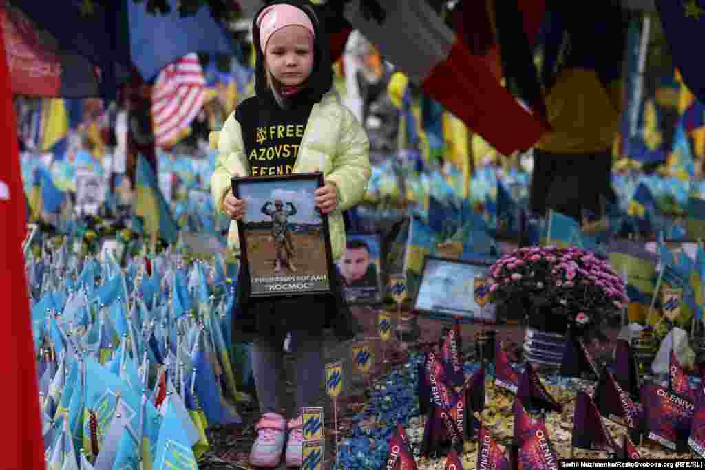 Дівчинка тримає портрет військового біля нароодного меморіалу пам&#39;яті загиблих оборонців України на Майдані Незалежності у Києві. Перші загиблі в історії триваючої російсько-української війни були під час гібридного захоплення Росією Крим у 2014 році.&nbsp; За 10 років Україна втратила десятки тисяч загиблими. Українська влада не розголошує дані про кількість загиблих та поранених. &nbsp;