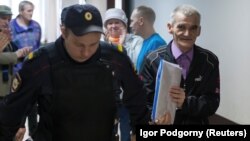 Yury Dmitriyev is escorted by a police officer upon his arrival for a court hearing in Petrozavodsk in June 2017.