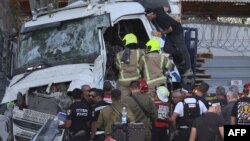 ისრაელის პოლიციელები და მაშველები სატვირთო ავტომობილთან, რომელიც ავტობუსის გაჩერებას შეეჯახა. თელ-ავივი, 27 ოქტომბერი, 2024. 