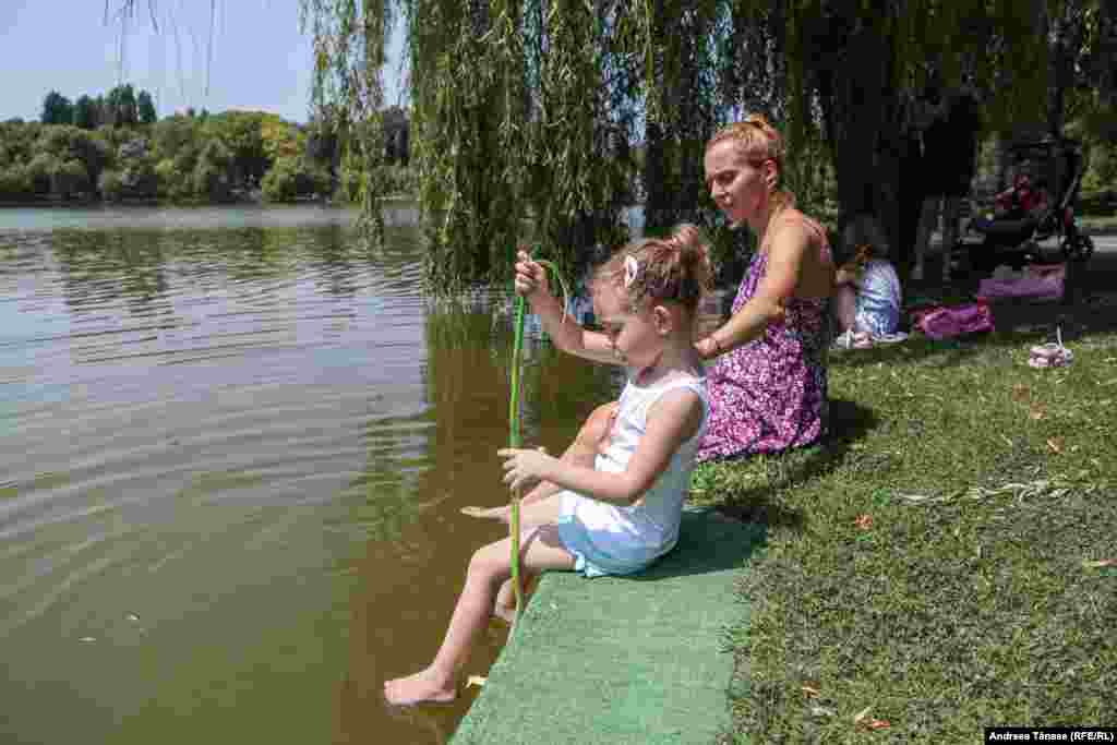 O femeie și fiica sa se răcoresc în lacul din Parcul Alexandru Ioan Cuza din București, din cauza temperaturilor ridicate.