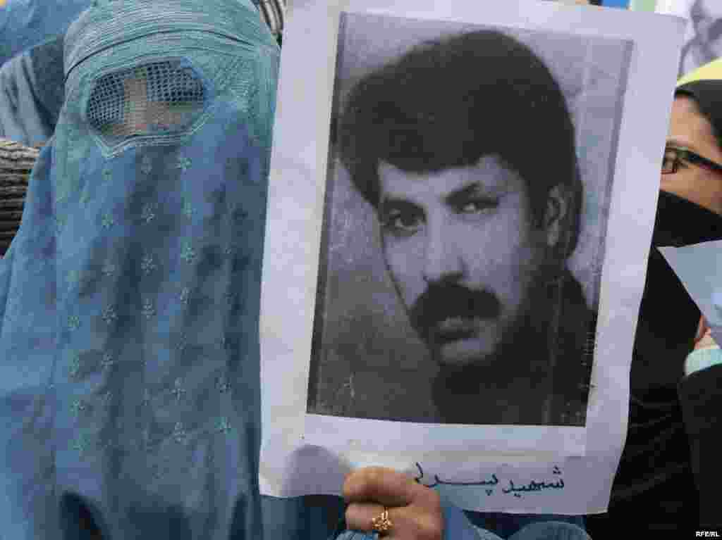 An Afghan woman holds a picture of a war victim during an antiwar protest. - Afghans gathered in Kabul on December 10 to demand that war criminals from three decades of war in Afghanistan be brought to justice. Photo by RFE/RL