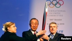 A staff member (left) adjusts the Olympic Torch while UN Secretary-General Ban Ki-moon (center) poses with International Olympic Committee (IOC) President Thomas Bach ahead of an IOC session in Sochi on February 6.