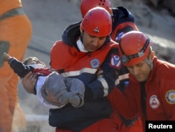 A rescue worker carries a young boy to an ambulance after he was found alive in a collapsed building in Ercis on October 24.