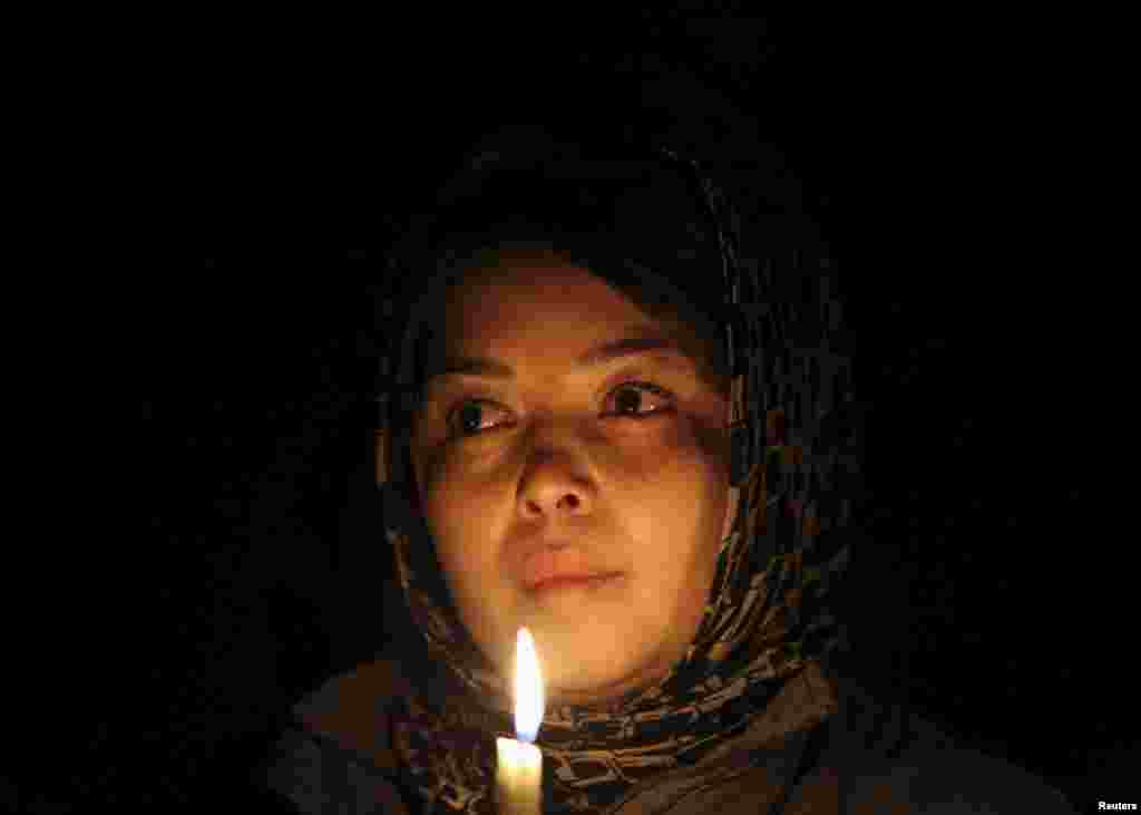 A woman holds a candle as she waits for the seven coffins during a protest procession in Kabul on November 10.