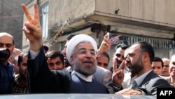 Hassan Rohani flashes a victory sign as he leaves a polling station after voting in Tehran on June 14.