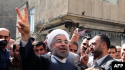 Iranian moderate presidential candidate Hassan Rohani (center) flashes the sign of victory as he leaves a polling station after voting in Tehran on June 14.