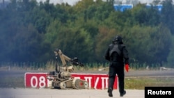 A police officer in protective clothing walks next to an explosive-disarming robot at Leipzig/Halle Airport in Schkeuditz, Germany, early last month after a drone was found near a runway. 