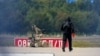Policajac u zaštitnoj opremi stoji pored robota za deaktiviranje eksploziva na aerodromu Leipzig/Halle u Njemačkoj, nakon što je u augustu u blizini piste pronađen dron.