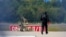 Policajac u zaštitnoj opremi stoji pored robota za deaktiviranje eksploziva na aerodromu Leipzig/Halle u Njemačkoj, nakon što je u augustu u blizini piste pronađen dron.