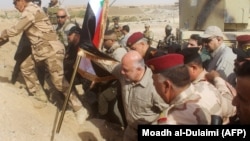 Iraqi Prime Minister Haidar al-Abadi prepares to erect a national flag in Al-Qaim to mark victory over Islamic State in November 2017. (file photo)