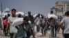 Palestinezët duke bartur në krah thasë me miell. 27 korrik 2025. 