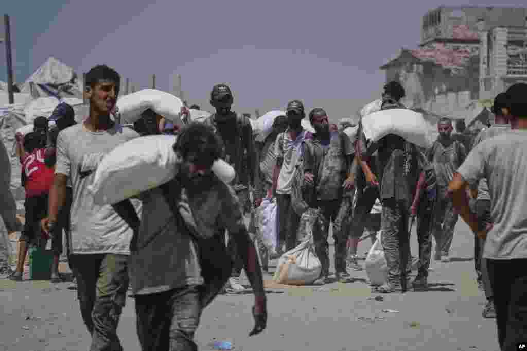 Palestinci nose vreće brašna istovarene iz konvoja humanitarne pomoći koji je stigao u Gazu iz sjevernog Pojasa Gaze, u nedjelju, 27. jula 2025.