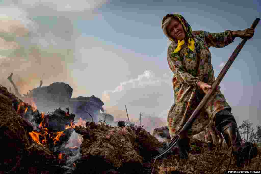 Lubov Multanova tends a smoldering moss fire. The smoke helps keep swarms of flies from pestering the reindeer. 