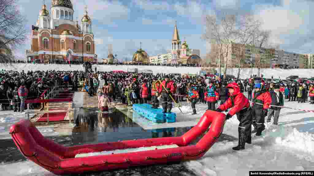 Перші сміливці заходять у воду, а рятувальники встановлюють гумовий човен, щоб люди не запливали далеко