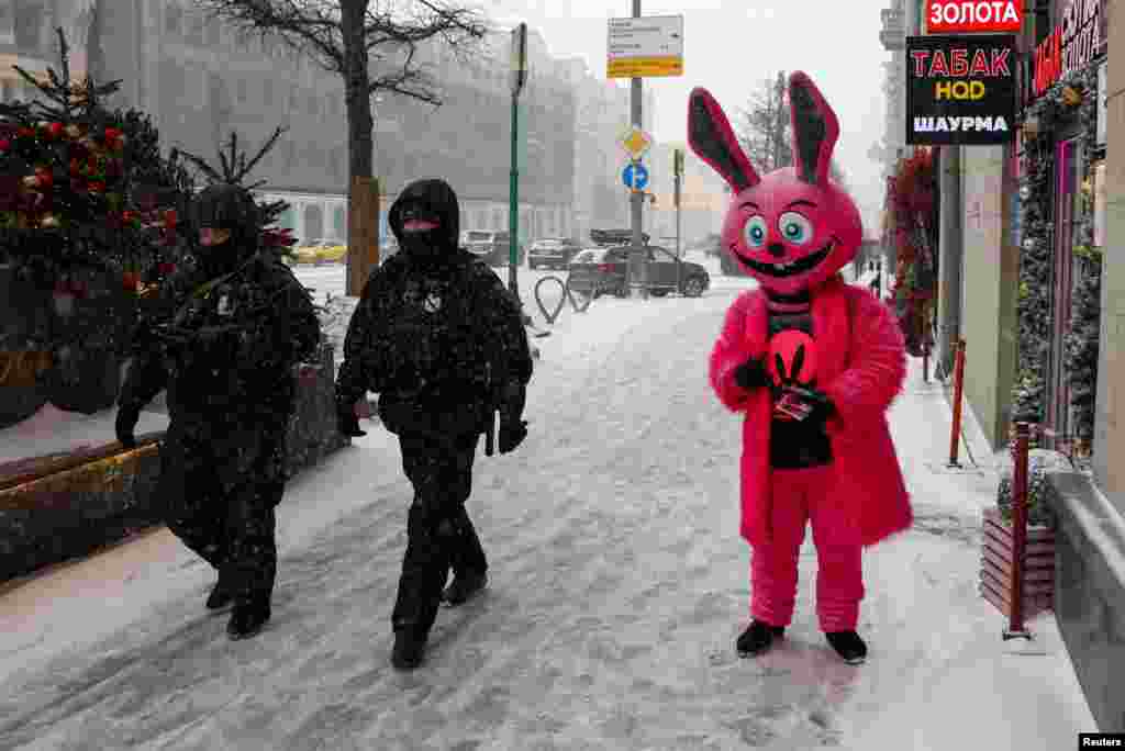 Российские полицейские идут по улице мимо человека, одетого в костюм кролика и рекламирующего секс-шоп, в снежный день в Москве, Россия, 16 февраля 2026 года. REUTERS/Рамиль Ситдиков