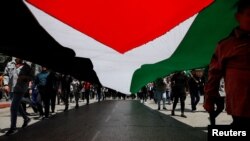پرچم فلسطینی‌ها در یک راهپیمایی اعتراضی در کرانه باختری که مقر تشکیلات خودگردان فلسطینی است