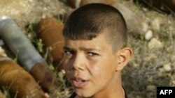 A boy holds an unexploded cluster bomb in the southern Lebanese village of Kunin near the border with Israel in October 2006.